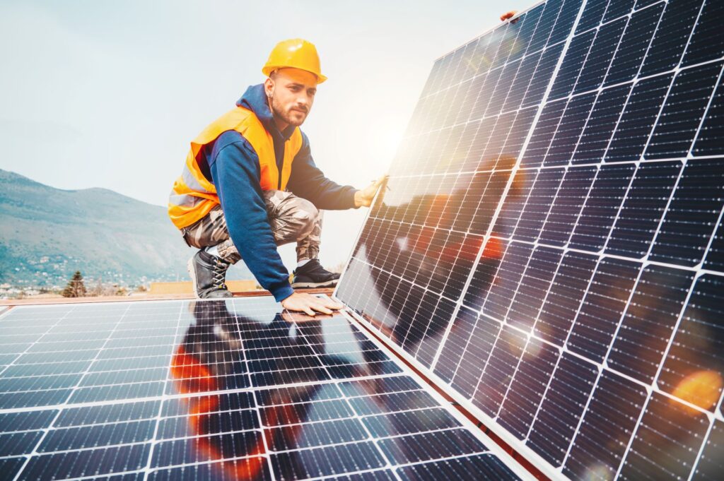 Techniker installiert eine PV-Anlage mit 10 kWp auf einem Hausdach bei Sonnenschein, symbolisiert die nachhaltige Energieerzeugung und den Wertzuwachs einer Immobilie durch erneuerbare Energien.