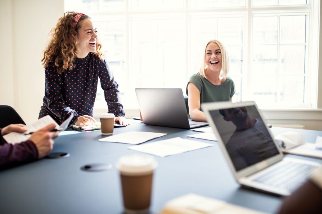 Ein lachendes Team bei einer Social Media Agentur, das in einem hellen Büro kreativ zusammenarbeitet