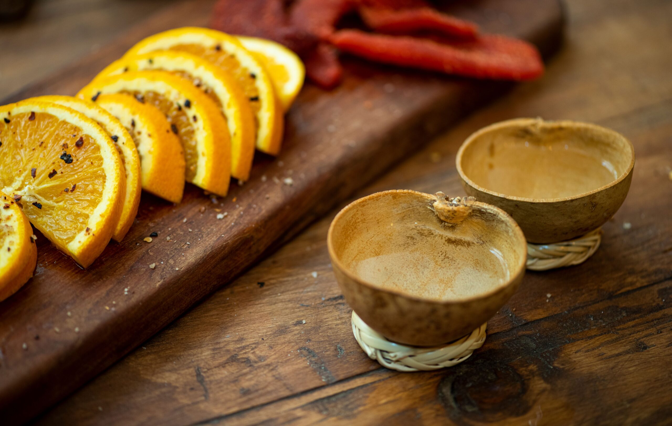 Geschnittene Orangen mit Chili-Gewürz und traditionelle mexikanische Trinkgefäße