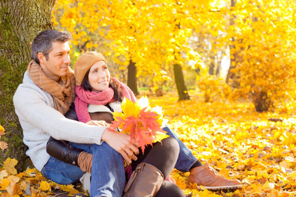 Ein Paar sitzt im Herbstlaub