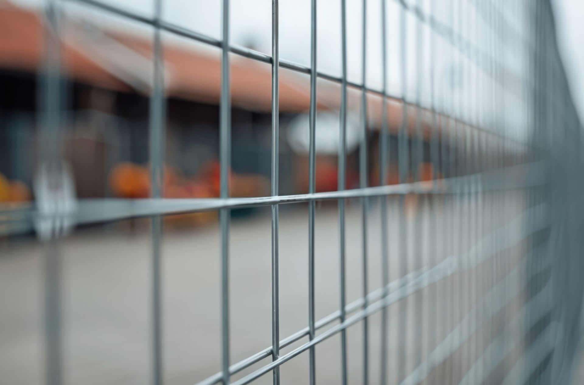 Nahaufnahme eines Bauzauns aus Metallgitter mit unscharfem Hintergrund