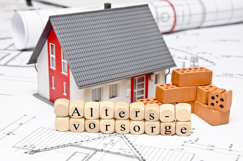 Minihaus mit Schrift „Altersvorsorge“ auf Bauplänen | Lkw-Arbeitsbühnen mieten