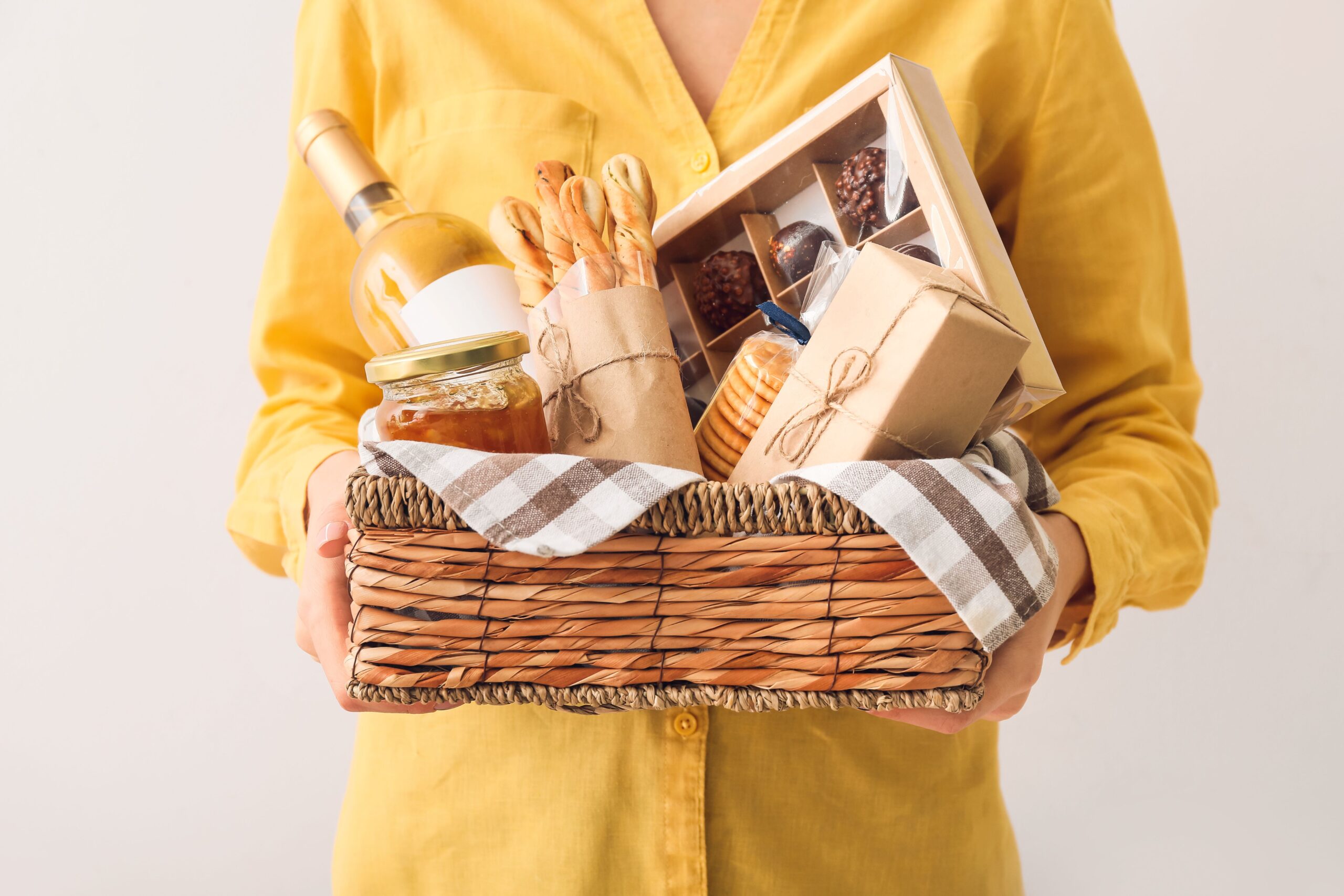 Person hält hochwertigen Präsentkorb mit Wein, Snacks und Geschenken