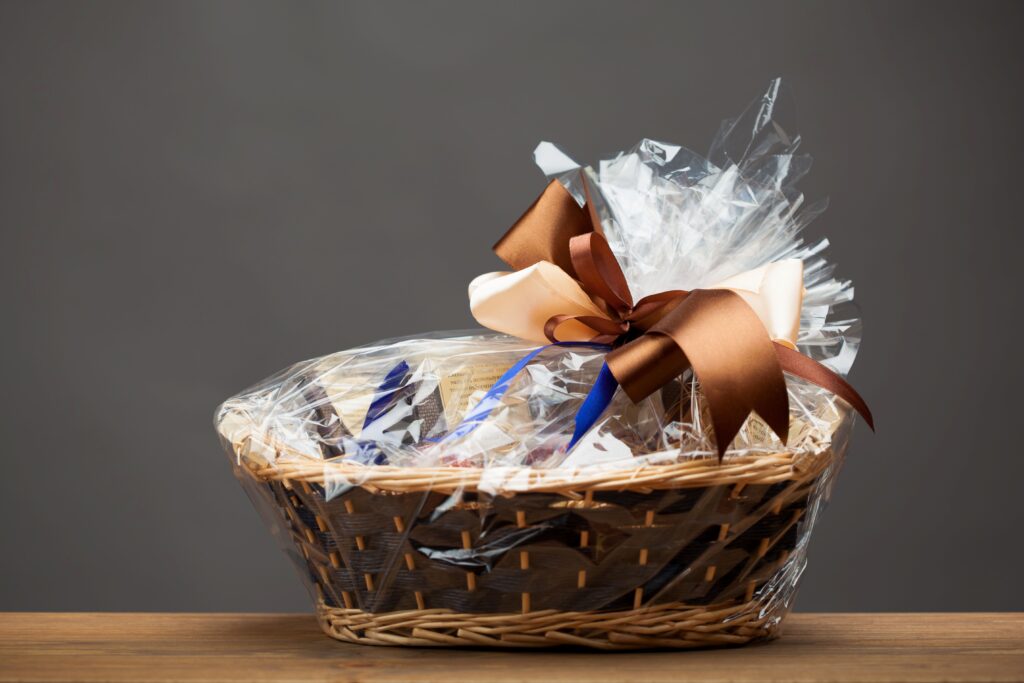 Geschenkkorb mit Schleife in Zellophan Folie verpackt auf Holztisch