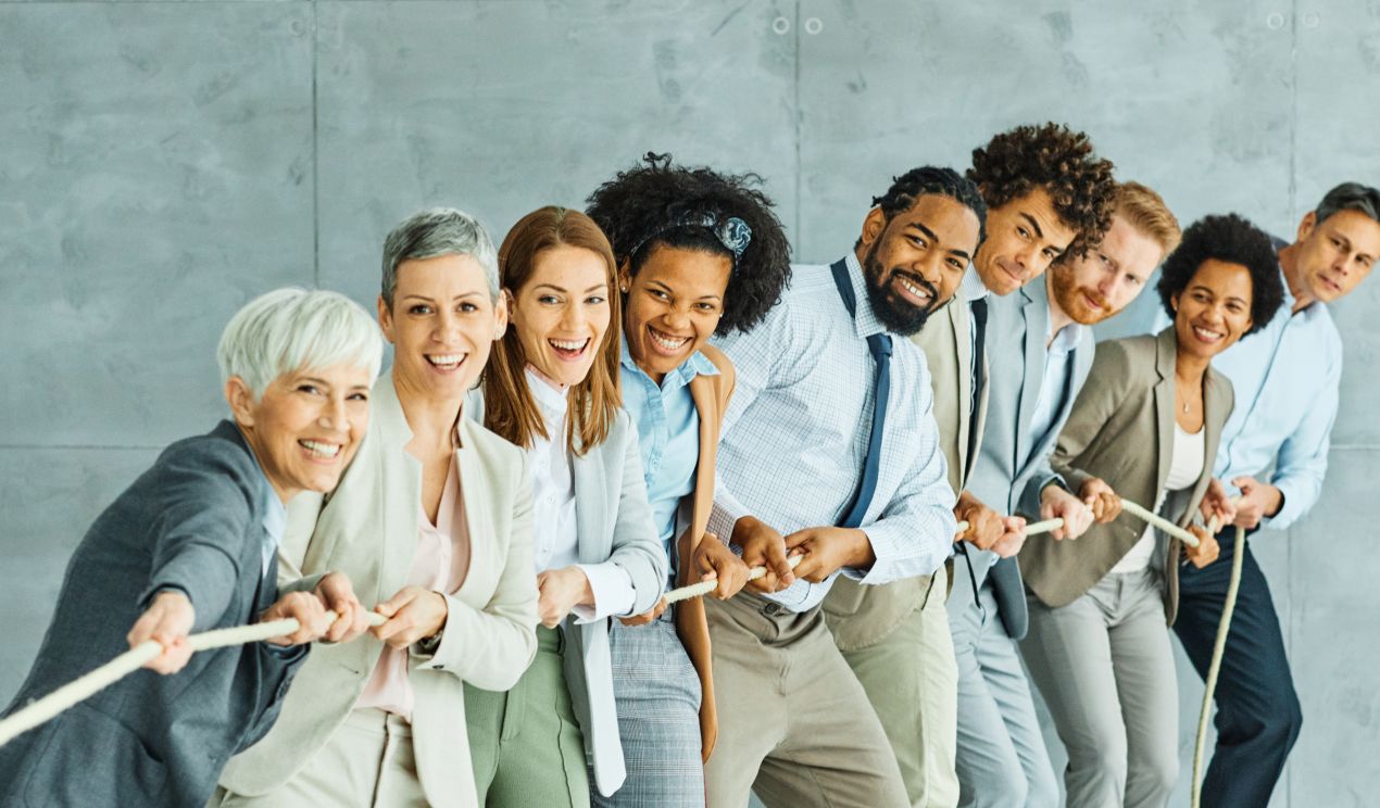 Laechelndes Team von Mitarbeitenden zieht gemeinsam an einem Seil – Symbol fuer Zusammenarbeit, Einsatz und Teamerfolg – Medaille kaufen