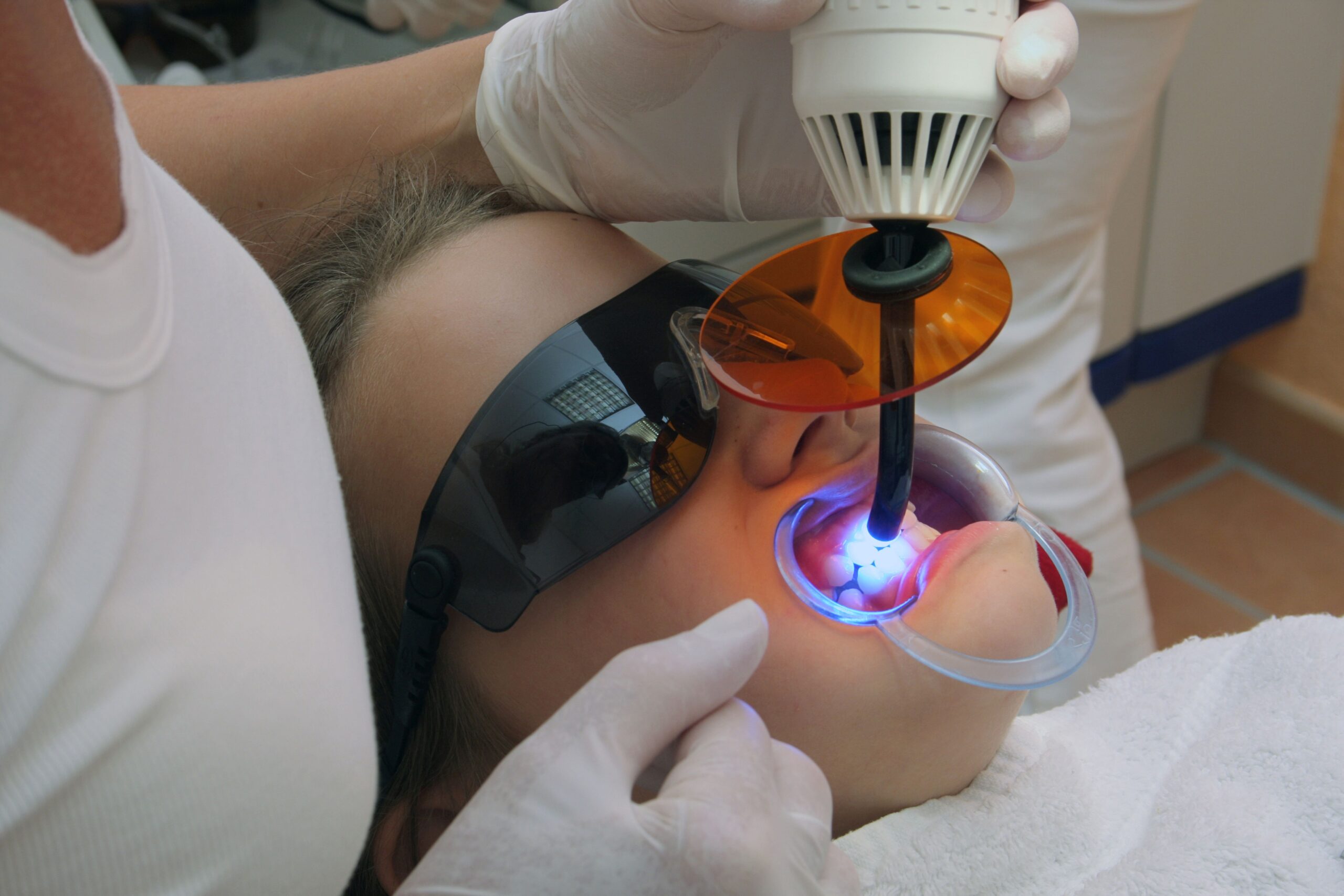 Patientin mit Schutzbrille erhält lichtbasierte Behandlung, moderne Technik beim Kieferorthopäde Duisburg